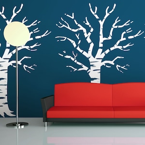 May include: A red sofa sits in front of a wall with a white silhouette of three trees. The wall is a dark blue colour.