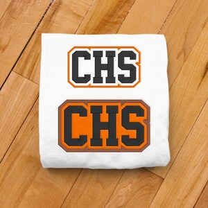 May include: White t-shirt with two orange and black embroidered patches that say "CHS" in a blocky font.