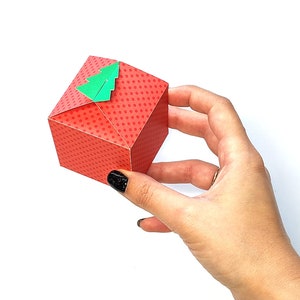 May include: A red gift box with white polka dots and a green paper Christmas tree on top.