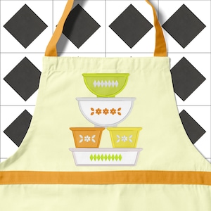 May include: A yellow, orange, and green kitchen apron with a stack of four vintage-style mixing bowls. The bowls are decorated with a floral pattern and a diamond pattern.