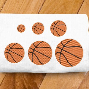 May include: A white fabric with five embroidered basketballs in different sizes. The basketballs are orange with black stitching and lines.