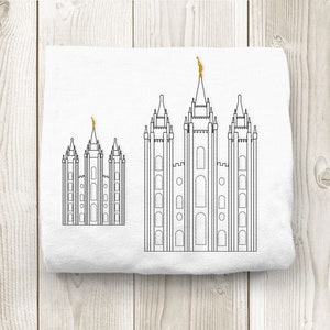 May include: A white t-shirt with a black line drawing of three temple buildings. The largest building is in the center and the two smaller buildings are on either side. The buildings have spires and windows.