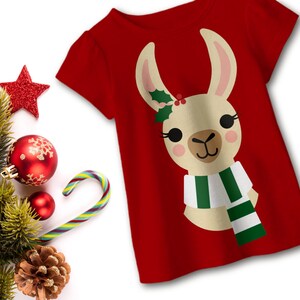 May include: Red t-shirt with a white llama wearing a green and white scarf and a holly sprig on its head.