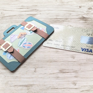 May include: A green suitcase with brown straps and a gift card with the text "GIFT CARD RECIPIENT" and the Visa logo. The gift card has a balance of &pound;125.