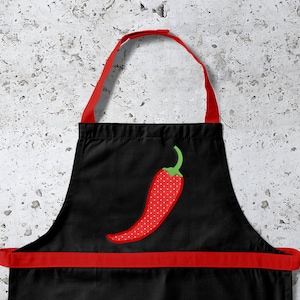 Peut inclure: Tablier de cuisine noir avec une bordure rouge et un piment rouge à pois blancs brodés sur le devant.