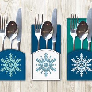 Puede incluir: Tres portacubiertos azules, blancos y verde azulado con un diseño de copo de nieve. Cada portacubiertos tiene un cuchillo, un tenedor y una cuchara.