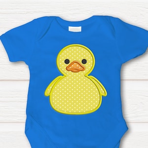 May include: A blue baby onesie with a yellow duck applique. The duck has white polka dots and a bright orange beak.