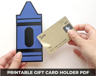 Könnte beinhalten: Ein druckbarer Geschenkkartenhalter in Form eines blauen Buntstiftes. Der Halter hat einen Schlitz zum Einlegen einer Geschenkkarte. Die Geschenkkarte ist eine goldene Vanilla-Geschenkkarte mit einem Guthaben von 25 €.