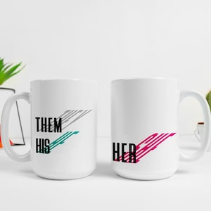 Może przedstawiać: Dwa białe kubki do kawy z czarnym tekstem i kolorowymi wzorami graficznymi. Kubek po lewej stronie ma napis "Them His" z turkusowym i szarym wzorem. Kubek po prawej stronie ma napis "Her" z różowym wzorem.