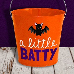 May include: Orange metal Halloween trick-or-treat bucket with a black bat and the text "a little BATTY" in white and purple lettering.