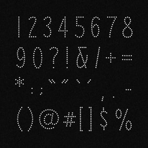 Puede incluir: Un fondo negro con caracteres punteados blancos, incluyendo números, signos de puntuación y símbolos. Los caracteres están dispuestos en tres filas. La primera fila incluye los números del 1 al 8. La segunda fila incluye los números 9 y 0, el signo de interrogación, el signo de exclamación, la ampersand, la barra diagonal, el signo más y el signo igual. La tercera fila incluye un asterisco, una coma, tres puntos, un paréntesis izquierdo, un símbolo de arroba, un signo de número, dos barras verticales, un signo de dólar y un signo de porcentaje.