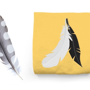 May include: A yellow t-shirt with a black and white embroidered feather design.