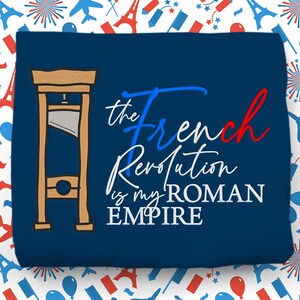 May include: A navy blue t-shirt with a white and red graphic of a guillotine and the text "The French Revolution is my ROMAN EMPIRE".