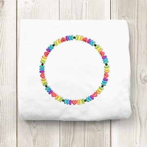 Könnte beinhalten: Ein weißes T-Shirt mit einem regenbogenfarbenen Kreis aus Herzen, der auf die Vorderseite gestickt ist.