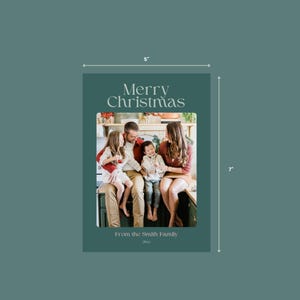 May include: A Christmas card with a green background and a photo of a family of four. The text "Merry Christmas" is at the top of the card, and the text "From the Smith Family" is at the bottom. The photo shows a family of four sitting on a counter in a kitchen. The family is smiling and looking at the camera.