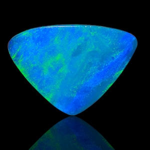 Op de afbeelding: Een driehoekige losse edelsteen met een levendig kleurenspel met dominante tinten elektrisch blauw en helder neongroen. Het oppervlak heeft een gepolijste afwerking met een duidelijk patroon van lichtreflecties over de steen.