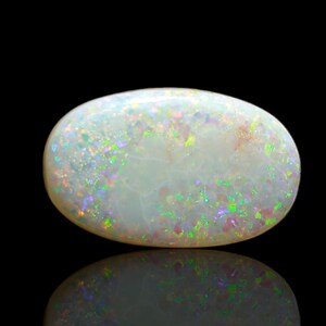 May include: An oval-shaped white opal gemstone featuring a smooth, polished surface with a vibrant play-of-color. The stone displays scattered flashes of bright green, pink, and purple light throughout its translucent, milky white body.