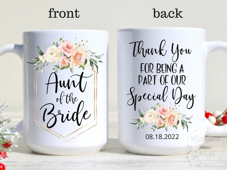 K&ouml;nnte beinhalten: Wei&szlig;e Keramiktasse mit Blumenmuster und goldenen Akzenten. Die Vorderseite der Tasse zeigt den Text "Aunt of the Bride". Die R&uuml;ckseite der Tasse zeigt den Text "Thank You for being a part of our Special Day 08.18.2022".