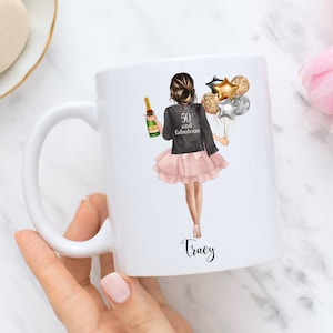 Peut inclure: Mug en c&eacute;ramique blanche avec un motif repr&eacute;sentant une femme tenant une bouteille de champagne et des ballons. Le texte "50 and fabulous" est sur la veste de la femme. Le nom "Tracy" est &eacute;crit au bas de la tasse.