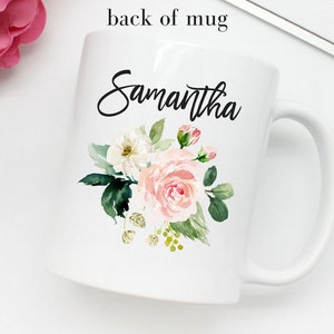 以下が含まれることがあります： 白いセラミック製のマグカップで、黒い花の模様と前面に「Samantha」という名前が印刷されています。