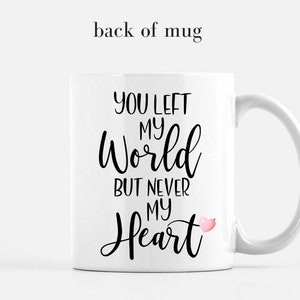 Puede incluir: Taza de cer&aacute;mica blanca con el texto "YOU LEFT MY WORLD BUT NEVER MY HEART" en escritura negra. Se incluye un peque&ntilde;o gr&aacute;fico de coraz&oacute;n rosa. La taza tiene un asa curva y est&aacute; sobre un fondo blanco.