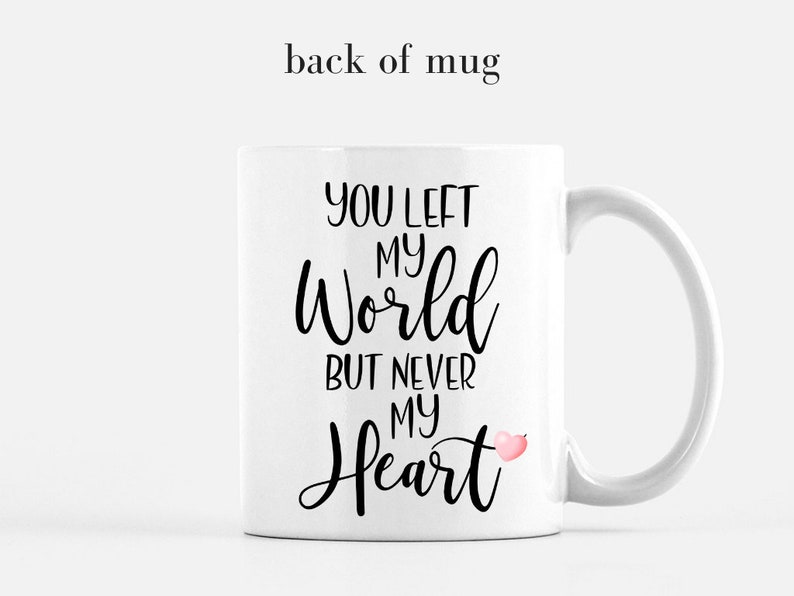 Puede incluir: Taza de cer&aacute;mica blanca con el texto "YOU LEFT MY WORLD BUT NEVER MY HEART" en escritura negra. Se incluye un peque&ntilde;o gr&aacute;fico de coraz&oacute;n rosa. La taza tiene un asa curva y est&aacute; sobre un fondo blanco.