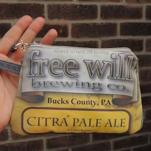 Puede incluir: Una bolsa con cremallera amarilla y marrón con el texto "free will brewing co. Bucks County, PA * CITRA PALE ALE 6 x 12 oz Bottles" impreso en ella.