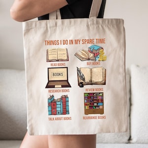 May include: A beige tote bag with the text "THINGS I DO IN MY SPARE TIME" and illustrations of books and related activities. The illustrations include reading, buying, researching, and reviewing books, as well as talking about and rearranging them.