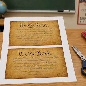 May include: A white sheet of paper featuring two identical printed copies of the United States Constitution preamble, each with a tan, aged parchment background and the black text We the People followed by the full introductory paragraph of the document.