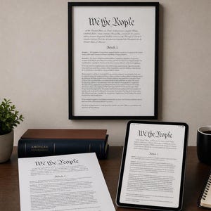 Pode incluir: Uma impressão emoldurada da Constituição dos EUA com as palavras "We the People". Um tablet e uma cópia impressa do documento também são visíveis, juntamente com um livro intitulado "American Government".
