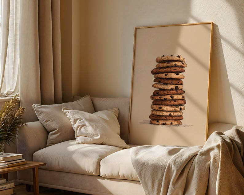May include: A vertical rectangular framed wall art print featuring a centered illustration of a tall, precarious stack of eleven round chocolate chip cookies against a solid, light beige background, with visible dark brown chocolate chips.