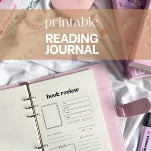 Op de afbeelding: Een roze leesdagboekmap met een geopende boekrecensiepagina. De pagina bevat velden voor titel, auteur, genre en pagina's, plus een ruimte voor een foto en een beoordelingssysteem. De woorden "printable READING JOURNAL" staan bovenaan.