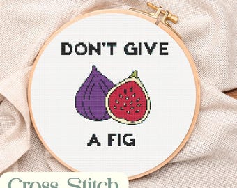 May include: A cross-stitch pattern in a wooden hoop features the text "DON'T GIVE A FIG" with fig illustrations. The design includes a whole purple fig and a sliced red fig. The words "Cross Stitch pattern" are also visible.