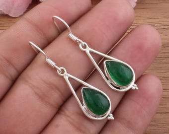 Può includere: Orecchini pendenti color argento con una pietra verde smeraldo a forma di goccia. Gli orecchini hanno un design semplice ed elegante con chiusura a gancio e un elemento decorativo nella parte inferiore.