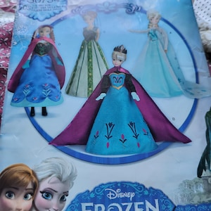 K&ouml;nnte beinhalten: Ein Schnittmuster mit den Charakteren von Disney's Frozen. Das Muster enth&auml;lt Bilder von Elsa- und Anna-Puppen in ihren ikonischen Outfits. Die Verpackung hat das Disney Frozen-Logo und den Text "11 1/2" DOLL".