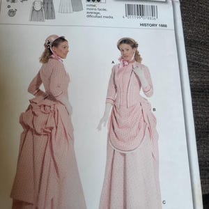May include: A Burda 7880 sewing pattern envelope for a historical 1888 style outfit. The package displays a pink dress with a small dark pattern, featuring a fitted jacket, a long skirt with a bustle, and a matching bonnet, in sizes 10 to 22.