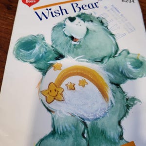 May include: A vintage Care Bears Wish Bear sewing pattern. The cover features a teal-colored bear with a white belly, a shooting star design, and the text "Wish Bear". The Care Bears logo is in the upper left corner.