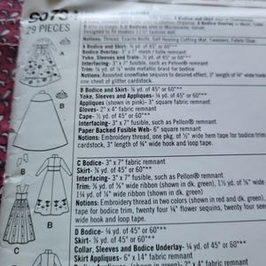 K&ouml;nnte beinhalten: Nahaufnahme eines Schnittmusters mit detaillierten Anweisungen und Diagrammen zur Herstellung verschiedener Kleidungsst&uuml;cke. Das Muster enth&auml;lt Ma&szlig;e und Stoffanforderungen sowie eine Liste der f&uuml;r jedes Design ben&ouml;tigten Zutaten. Das Muster ist mit der Nummer "9073" und "29 TEILE" gekennzeichnet.