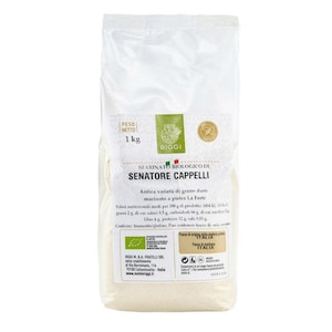 Könnte beinhalten: Ein transparenter Beutel mit Bio-Senatore Cappelli Mehl, wiegt 1 kg. Die Verpackung hat ein grünes und weißes Etikett mit italienischem Text, Nährwertangaben und dem Riggi-Markenlogo. Das Mehl wird aus altem Hartweizen hergestellt.