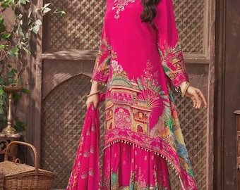 May include: A vibrant fuchsia-colored salwar kameez ensemble. The long-sleeved tunic and matching skirt feature a detailed, colorful print of architectural elements and floral designs. The outfit is worn by a person.