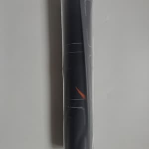 Op de afbeelding: Een opgerolde zwarte mat, verpakt in doorzichtig plastic. De mat heeft witte lijnen en een oranje ontwerp. Dit is waarschijnlijk een yogamat of een vergelijkbaar fitnessaccessoire.