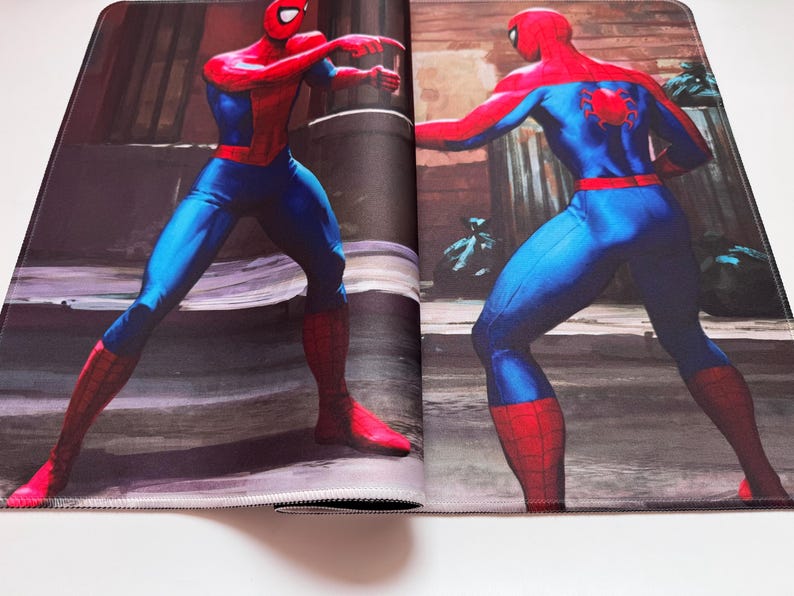 Puede incluir: Alfombrilla de rat&oacute;n con una ilustraci&oacute;n de c&oacute;mic de Spider-Man. El superh&eacute;roe se muestra con su cl&aacute;sico traje rojo y azul, con un dise&ntilde;o de telara&ntilde;a en la espalda. El fondo tiene un entorno urbano borroso.