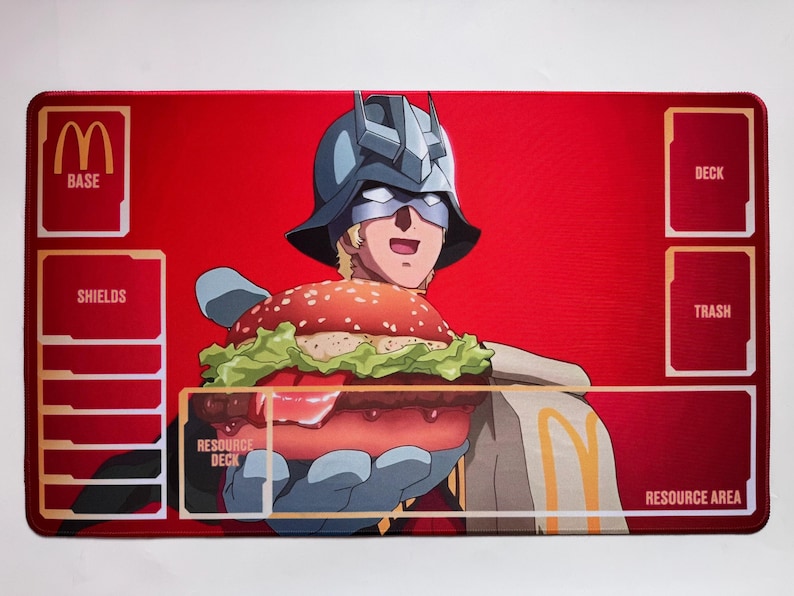 Puede incluir: Una alfombrilla de juego rectangular roja con un personaje de dibujos animados con casco sosteniendo una gran hamburguesa. El logotipo de McDonald's es visible, junto con cuadros de texto etiquetados como "BASE", "SHIELDS", "DECK", "TRASH" y "RESOURCE AREA".