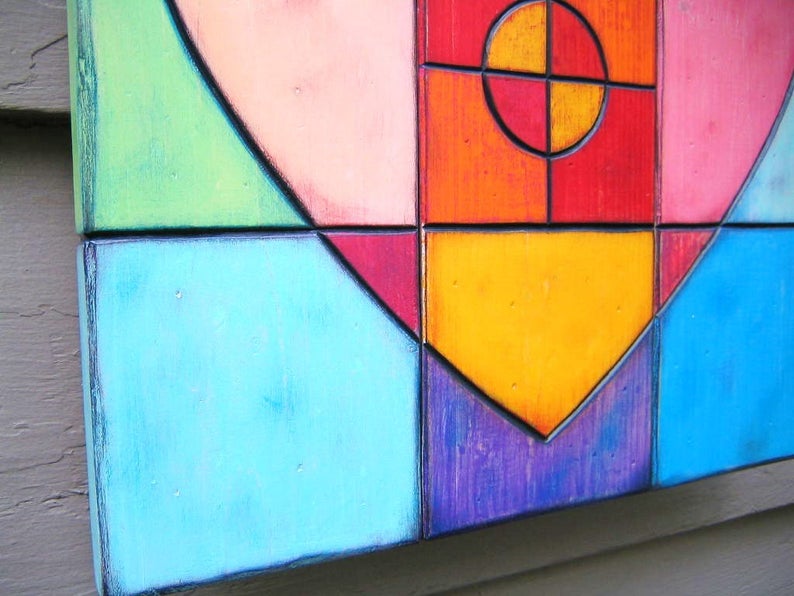 May include: A colorful geometric heart-shaped wall art piece made of wood. The heart is made up of squares and rectangles in shades of green, pink, red, orange, yellow, blue, and purple.