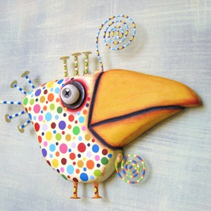 May include: A whimsical, colorful bird sculpture with a large orange beak and a body covered in polka dots. The bird has a large, expressive eye and decorative wire accents. The sculpture is mounted on a light blue background.