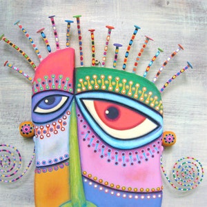 May include: A colorful, abstract mask with a green, pink, blue, and orange face. The mask has two large eyes with white pupils and a spiky, multi-colored hairpiece.