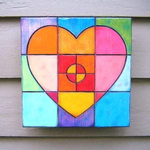 May include: A colorful heart-shaped mosaic made of square tiles. The tiles are arranged in a pattern of red, orange, yellow, green, blue, and pink. The heart is surrounded by a border of purple tiles.
