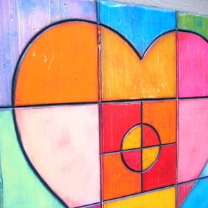 May include: A colorful wooden heart-shaped wall art piece made of squares in shades of orange, pink, red, blue, green, and purple.
