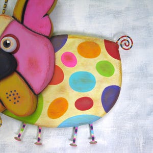 Puede incluir: Una escultura de perro de madera caprichosa y colorida con un cuerpo de lunares. El perro presenta orejas rosas, una cara amarilla y patas multicolores. La cola es un dise&ntilde;o en espiral. Una pieza decorativa divertida.