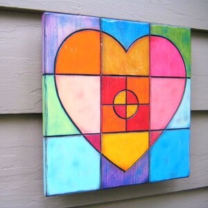 May include: A colorful heart-shaped mosaic made of square tiles in shades of blue, green, orange, pink, red, and purple. The tiles are arranged in a geometric pattern to create a heart shape.